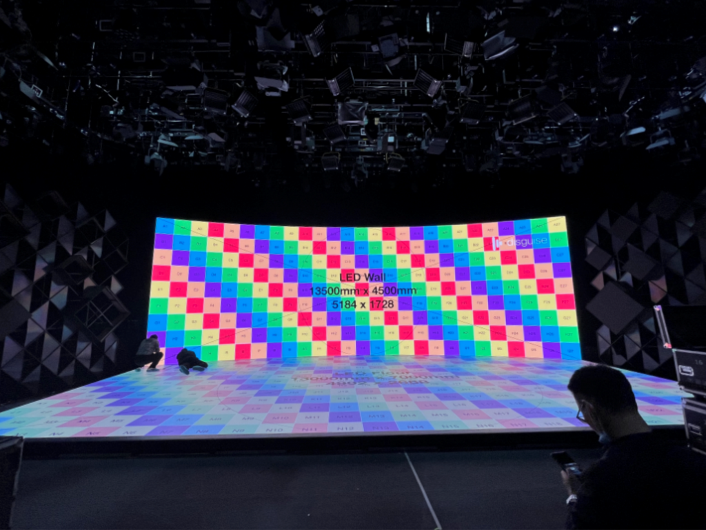 Curved LED wall and LED floor displaying a colour calibration checkerboard, labelled 13500mm by 4500mm at 5184 x 1728 pixels