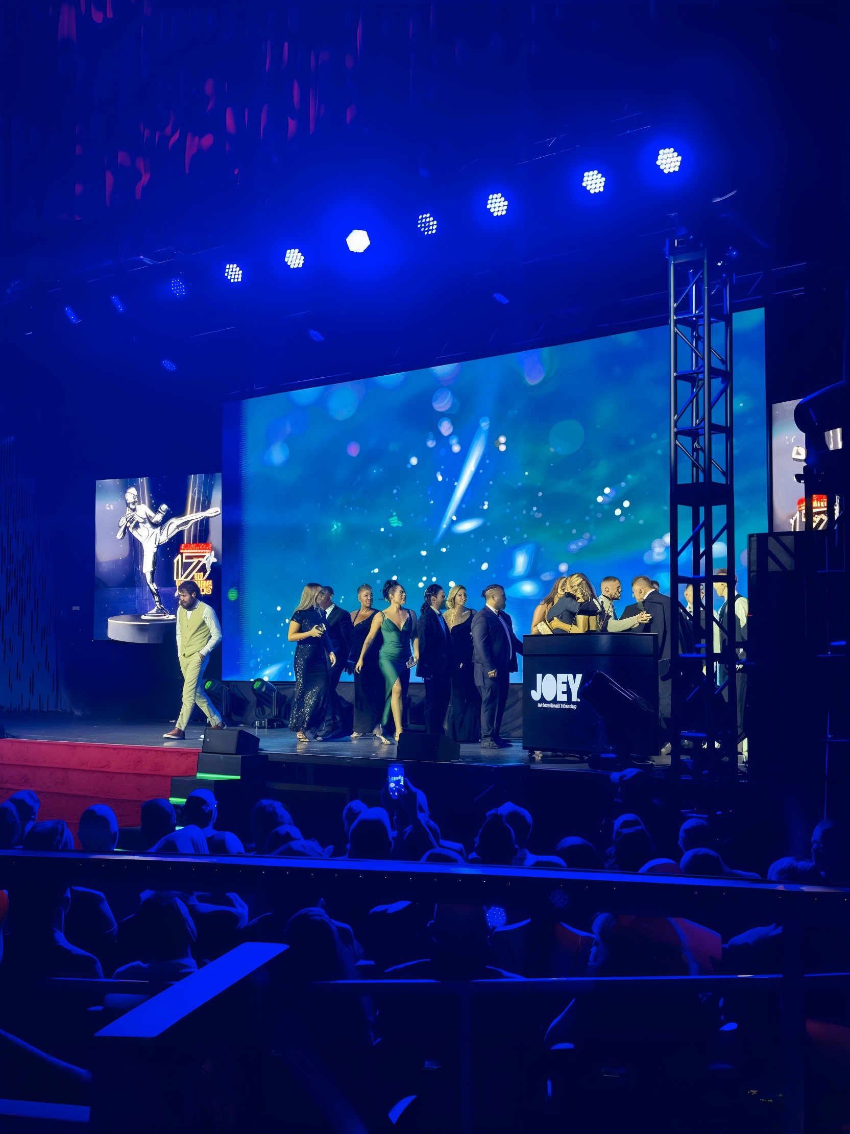 Wide view of the HOLODECK HoloPod™ podium on the World MMA Awards stage with presenters and video wall