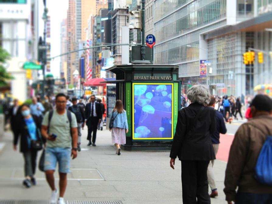 Pedestrians passing a HOLODECK LED 2.6mm digital panel on the Bryant Park News stand, 42nd Street, Manhattan