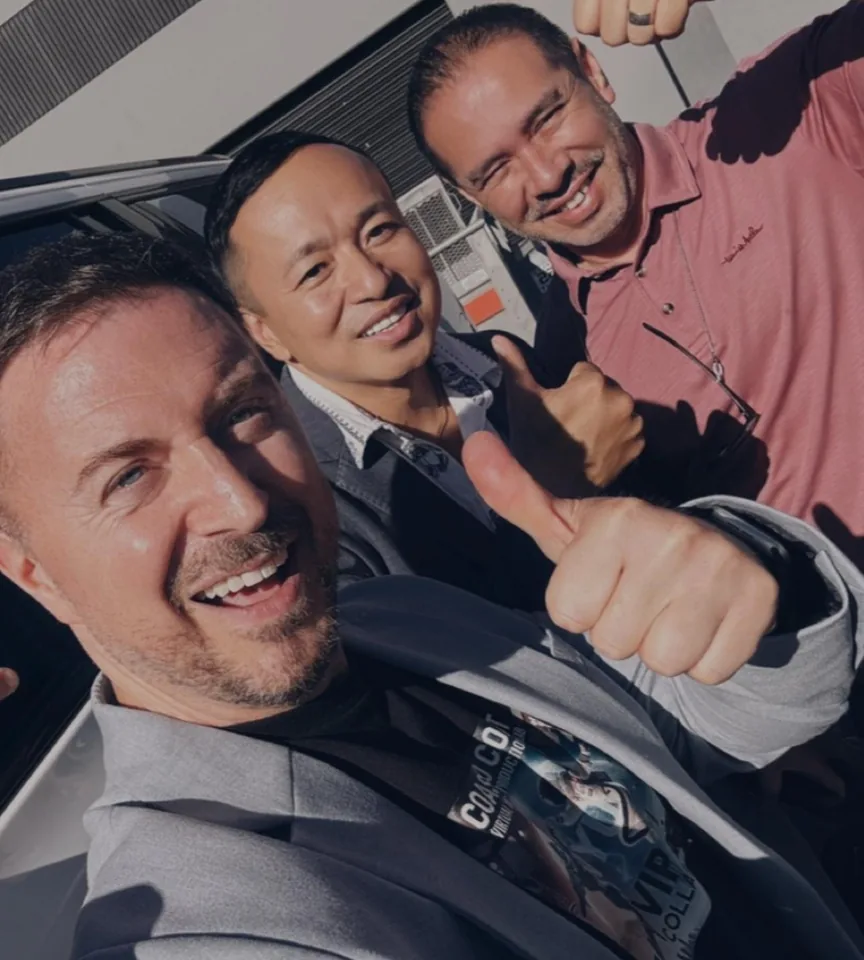 Three HOLODECK LED partners giving thumbs up in a selfie by a car