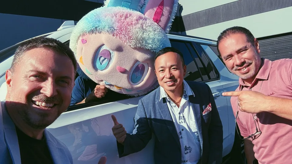 Three men posing in front of a colorful character display