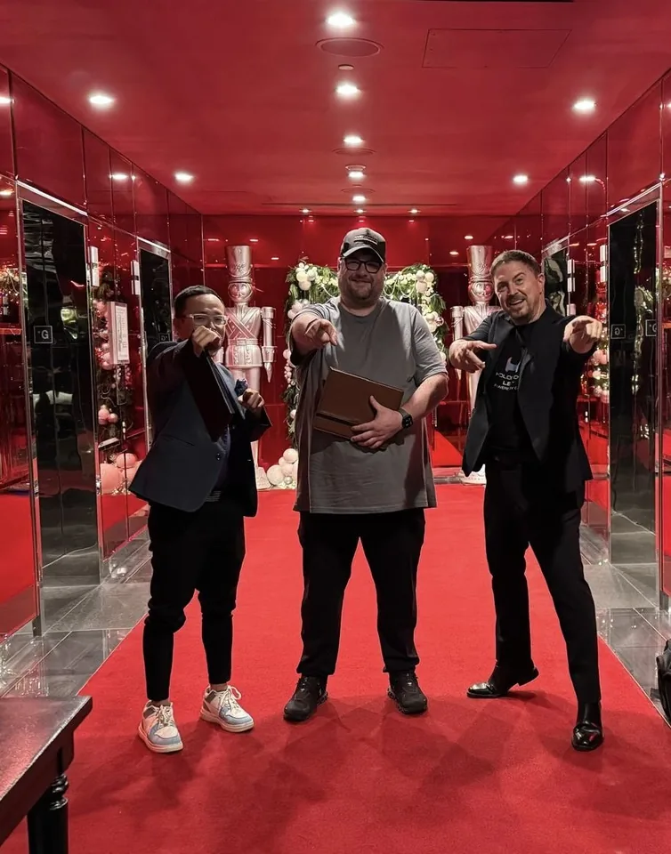 Three men posing on a red carpet