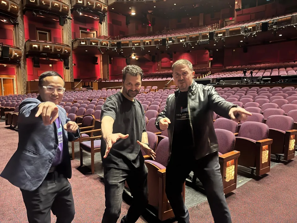 Three men posing inside a theater
